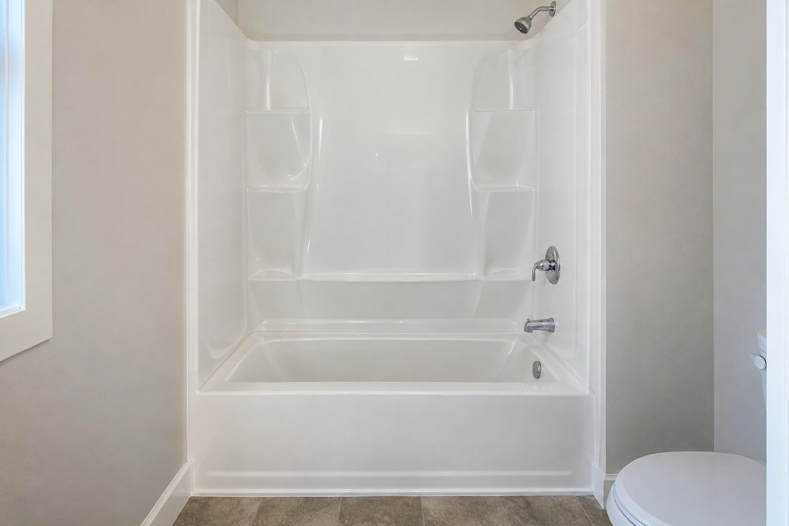 White one-piece acrylic tub and shower unit with molded shelves set into an alcove